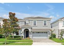 Charming two-story home with a gray exterior, well-manicured lawn, and a brick-paved driveway at 1521 Flange Dr, Davenport, FL 33896
