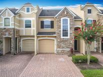 Attractive townhome with brick driveway, manicured lawn, and stone facade, creating inviting curb appeal at 15822 Woodland Spring Ct, Orlando, FL 32828
