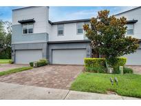 Modern townhome featuring a brick driveway, two-car garage, manicured landscaping, and a stylish architectural design at 1624 Little Wren Ln, Winter Park, FL 32792