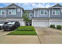 Charming exterior view of townhomes, featuring muted blue siding, a two-car garage, and landscaping at 1932 Terrapin Rd, Ocoee, FL 34761