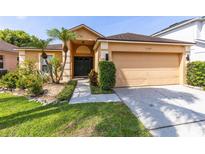 Inviting single-story home featuring a two-car garage, manicured landscaping, and a charming entryway at 3224 Holland Dr, Orlando, FL 32825