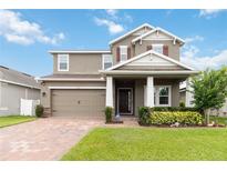 Charming two-story home featuring a brick driveway, manicured lawn, and welcoming covered porch at 4759 Riverwalk Dr, St Cloud, FL 34771
