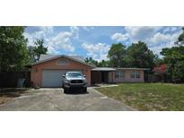 Charming single-story home featuring stucco exterior, attached garage, and mature landscaping on a sunny day at 5612 Ridgeway Dr, Orlando, FL 32819