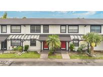 Charming townhome with a red door, a well-kept lawn and beautiful palm trees at 5662 Royal Pine Blvd # 24, Orlando, FL 32807