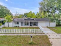 Charming single-story home featuring a white picket fence, well-manicured lawn, and attached one-car garage at 614 S Amelia Ave, Deland, FL 32724