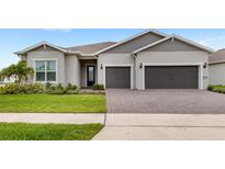 Well-maintained home exterior featuring a two-car garage, paver driveway, and manicured landscaping at 6348 Mossy Oak Rd, St Cloud, FL 34771