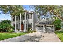 Stately two-story home with a three-car garage, gray exterior, white pillars, black shutters, and a well-manicured lawn at 11425 Claymont Cir, Windermere, FL 34786