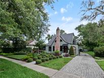 Charming home featuring a brick chimney, lush landscaping, and a paved driveway at 1227 Golden Ln, Orlando, FL 32804