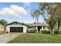 Charming white brick home featuring a black garage door and beautifully landscaped front yard at 7307 Grace Rd, Orlando, FL 32819