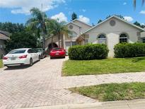 Inviting home featuring a brick driveway, manicured lawn, and tropical landscaping at 807 Knightsbridge Cir, Davenport, FL 33896