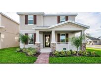 Charming two-story home featuring a welcoming front porch and professionally landscaped front yard at 9106 Cut Shot Dr, Winter Garden, FL 34787