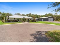 Charming single-story home with well-maintained landscaping and a circular driveway, plus a large garage or workshop in the background at 920 Grand Ave, Orange City, FL 32763