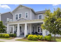 Charming two-story home with a welcoming front porch, manicured landscaping, and a light gray exterior at 1206 Civitas Way, Winter Garden, FL 34787
