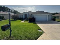 Charming single-story home with a well-manicured lawn, long driveway, and two-car garage at 13655 Se 97Th Terrace Rd, Summerfield, FL 34491