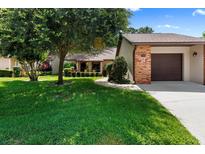 Charming single-story home featuring a well-manicured lawn, mature trees, and a brick-accented garage at 154 Golf Club Dr # 154, Longwood, FL 32779