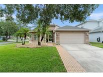 Charming single-story home with a well-manicured lawn, palm trees, and a two-car garage at 182 Westmoreland Cir, Kissimmee, FL 34744