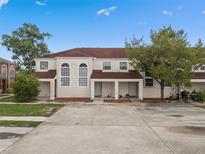 Inviting townhome featuring a red roof, private entrances, and lush trees for added shade and curb appeal at 214 Majors Ln # B, Kissimmee, FL 34743