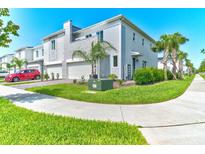 Modern townhome with a two-car garage, stone accents, lush landscaping, and a red car parked in driveway at 224 Nine Iron Dr, Davenport, FL 33896