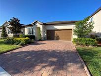 Charming single-story home with a well-maintained lawn and brick paved driveway leading to a two-car garage at 312 Irving Bend Dr, Groveland, FL 34736