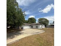 Single story home with a large driveway, well-manicured lawn, and mature trees at 337 Live Oak Blvd, Sanford, FL 32773
