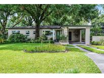 Charming single-story home with lush front yard, mature trees, and covered carport at 424 E Muriel St, Orlando, FL 32806