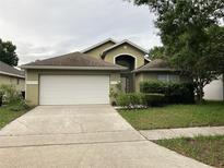 Inviting single-Gathering home featuring an attached two-car garage and well-manicured lawn at 11236 Rouse Run Cir, Orlando, FL 32817