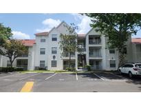 A view of the exterior of the white condo building featuring balconies, stairs, and parking spaces at 11588 Westwood Blvd # 1523, Orlando, FL 32821
