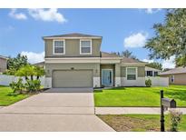 Charming two-story home with a well-manicured lawn, a two-car garage, and a light-blue front door at 11616 Thacker Dr, Clermont, FL 34711