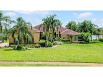 Charming home boasts manicured landscaping, lush lawn and mature palm trees in a tranquil setting at 13626 Sunset Lakes Cir, Winter Garden, FL 34787