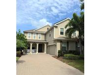 Charming two-story home with a tan exterior, attached garage, landscaped yard and a brick paver driveway at 14744 Spotted Sandpiper Blvd, Winter Garden, FL 34787
