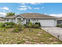 Charming single-story home with a two-car garage and lush garden in the front yard at 1907 Myakka Ct, Poinciana, FL 34759