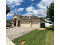 Charming home with a three car garage, brick paved driveway, and well-maintained landscaping, perfect for suburban living at 2051 Sandy Garden Ln, Winter Garden, FL 34787