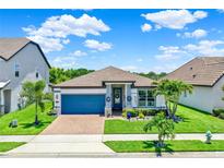 Charming single-story home featuring a blue garage door, well-manicured lawn, and vibrant landscaping at 2390 Standing Rock Cir, Oakland, FL 34787