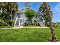 Inviting exterior featuring a well-maintained blue condo with lush landscaping and a staircase leading to the entrance at 2501 Grassy Point Dr # 107, Lake Mary, FL 32746