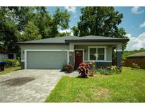Charming single-story home features a gray exterior, brick driveway, and well-maintained landscaping at 309 E 13Th St, Apopka, FL 32703