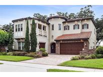 Stunning two-story stucco home featuring a three-car garage, tile roof, and beautifully landscaped front yard at 617 Canopy Estates Dr, Winter Garden, FL 34787