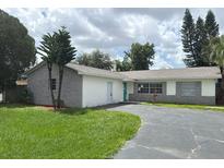 Charming single-story home features a gray brick facade, bright green front door, and a spacious driveway at 624 American Heritage Pkwy, Orlando, FL 32809