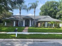 Charming home featuring a lush lawn, mature palm trees, and elegant architectural details at 831 Royalwood Ln, Oviedo, FL 32765