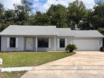 Charming single-story home with a two-car garage, a well-maintained lawn, and mature trees in the background at 1050 Reading Ct, Winter Park, FL 32792