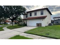 Two story home featuring a white exterior, tile roof, two car garage, and a well manicured front yard at 16631 Lazy Breeze Loop, Clermont, FL 34714