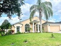 Charming single-story home featuring a stucco facade, manicured lawn, and a mature palm tree at 1672 Canoe Creek Rd, Oviedo, FL 32766