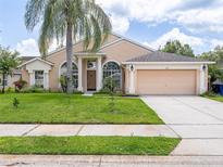 Charming single-story home with a well-maintained lawn, mature landscaping, and a two-car garage at 1672 Canoe Creek Rd, Oviedo, FL 32766