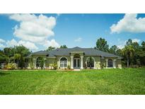Inviting single-story home featuring arched windows, a symmetrical facade, and meticulously manicured lawn at 19951 Quinlan St, Orlando, FL 32833