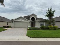 Charming home featuring a paver driveway, a two-car garage, and well-maintained landscaping at 541 Arena Dr, Davenport, FL 33837