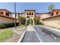 Beautiful condo with terra cotta tile roof, beige stucco, and lush tropical landscaping at 5500 Metrowest Blvd # 203, Orlando, FL 32811
