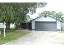 Charming home featuring a gray exterior, a large two-car garage, and a front yard with a large tree at 6849 Palomino Dr, Lakeland, FL 33811
