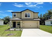 Two-story home featuring a beige exterior, attached two-car garage, and well-maintained front lawn at 1303 Congo Ct, Kissimmee, FL 34759