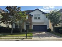 Charming two-story home with a stone facade, paver driveway, lush landscaping, and a two-car garage at 137 Drayton Ave, Davenport, FL 33837
