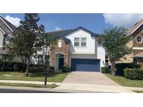Charming two-story home featuring stone accents, blue garage door, and a well-maintained landscaped front yard at 137 Drayton Ave, Davenport, FL 33837