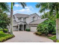 Stunning two-story home with lush landscaping and circular brick driveway and a three-car garage at 14038 Bluebird Park Rd, Windermere, FL 34786
